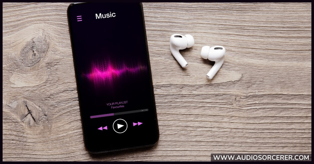 Phone with a music app open and earbuds on a table.